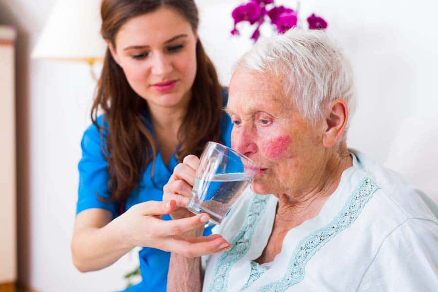 nurse helping elderly patient to drink