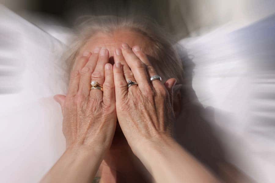 Close up portrait of woman covering her face with hands in blurred background.