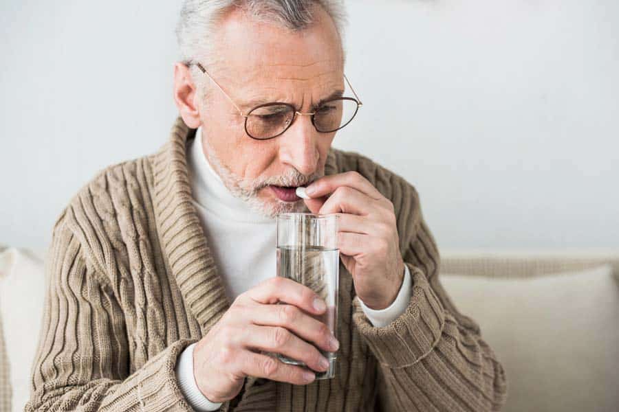 Man taking NSAIDs with a glass of water